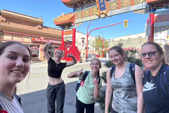 Friends pose by Victoria Chinatown Gate on a scavenger hunt and city highlights walking tour in downtown BC