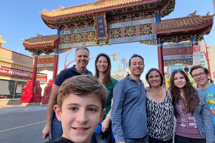 Family photo at Victoria Chinatown Gate on a city highlights scavenger hunt walking tour in downtown