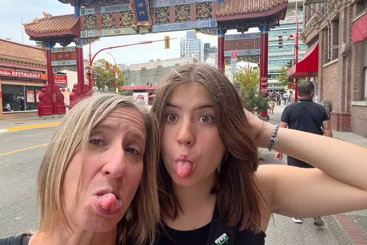 Visitors pose by Victoria Chinatown Gate on a scavenger hunt walking tour of city highlights downtown