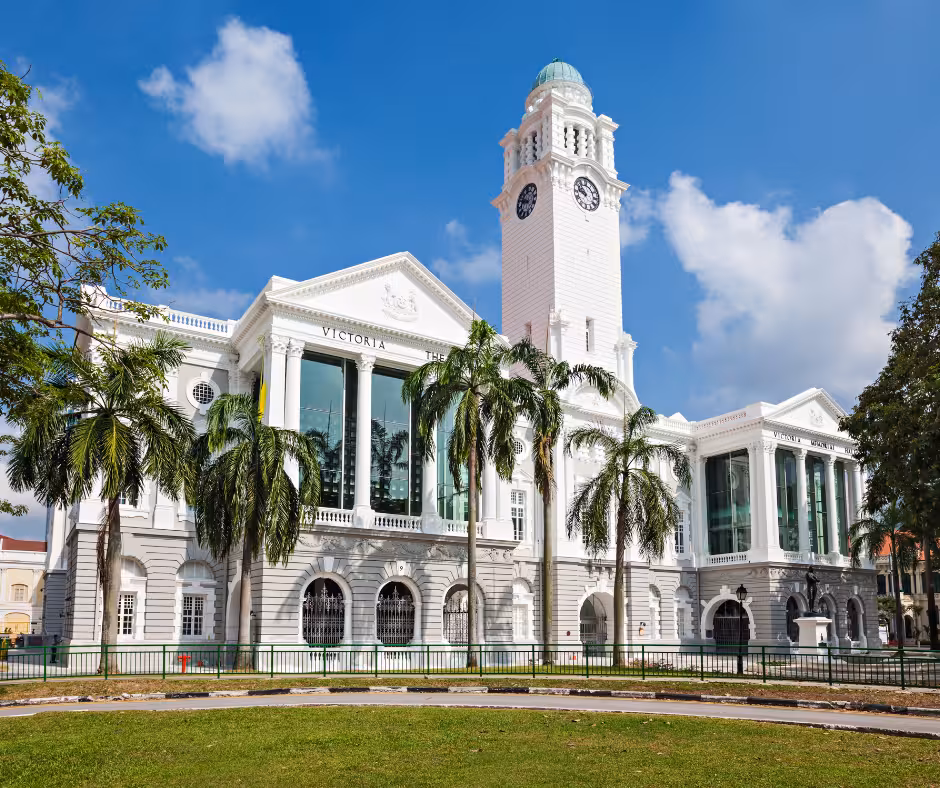 Victoria Theatre and Concert Hall with palm trees, a historic landmark in Singapore's Civic District under a clear sky.