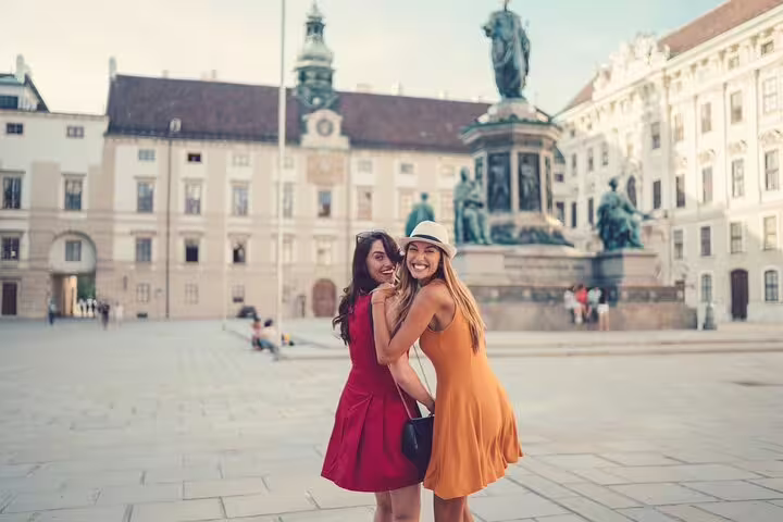 Two smiling women explore Vienna's historic Hofburg Palace, a highlight of the private tour featuring churches and local delights.