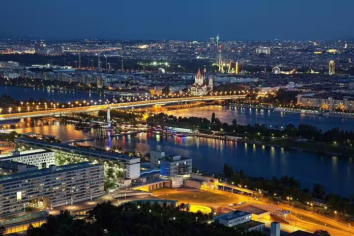 Aerial view of Vienna at night with illuminated bridges and the Danube River, perfect for a private city tour.