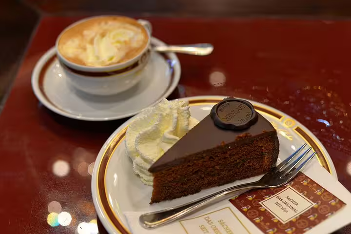 Vienna tour highlight: Indulge in authentic Sachertorte with whipped cream and coffee, capturing the essence of Austrian culinary delights.