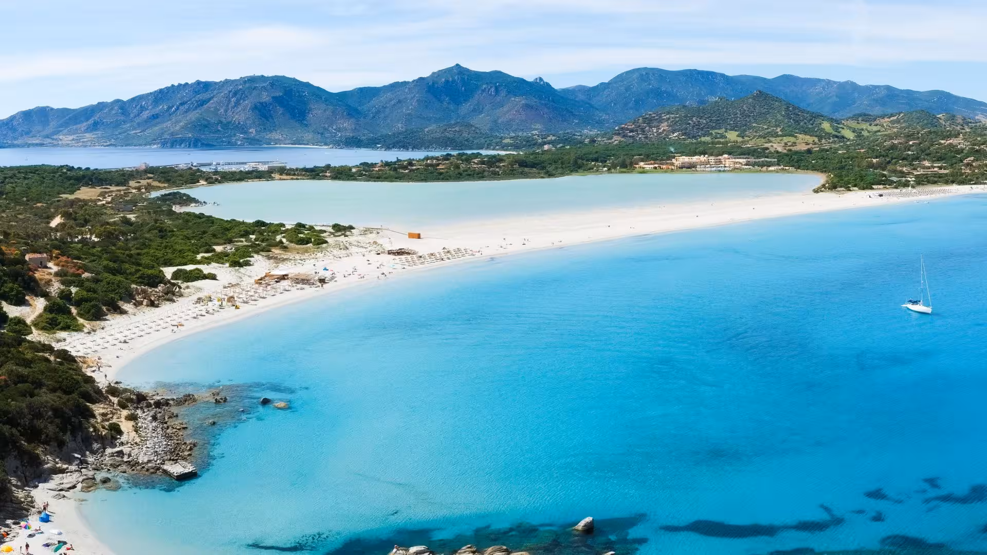 Panoramic beach scene in Villasimius with clear blue waters, perfect for RIB rental exploration for up to eight people.