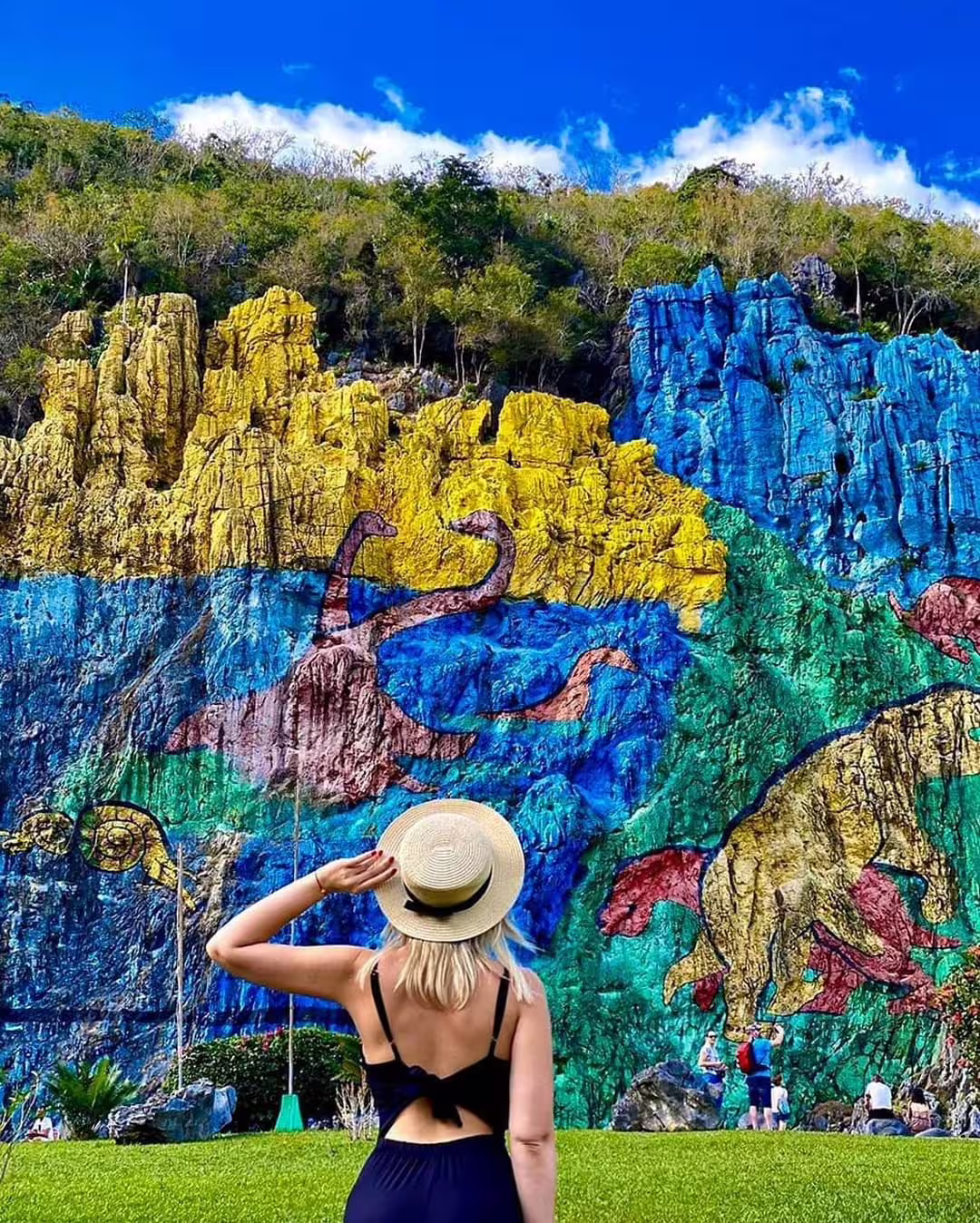 Traveler views Viñales Valley Mural de la Prehistoria, colorful cliff art on Cuba cultural tour from Havana