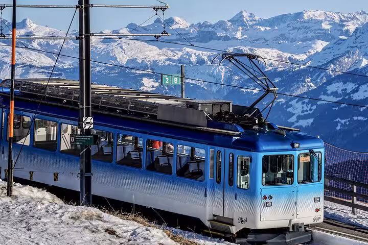 Vintage blue train traversing snowy Swiss mountains, offering breathtaking views and a unique travel experience.