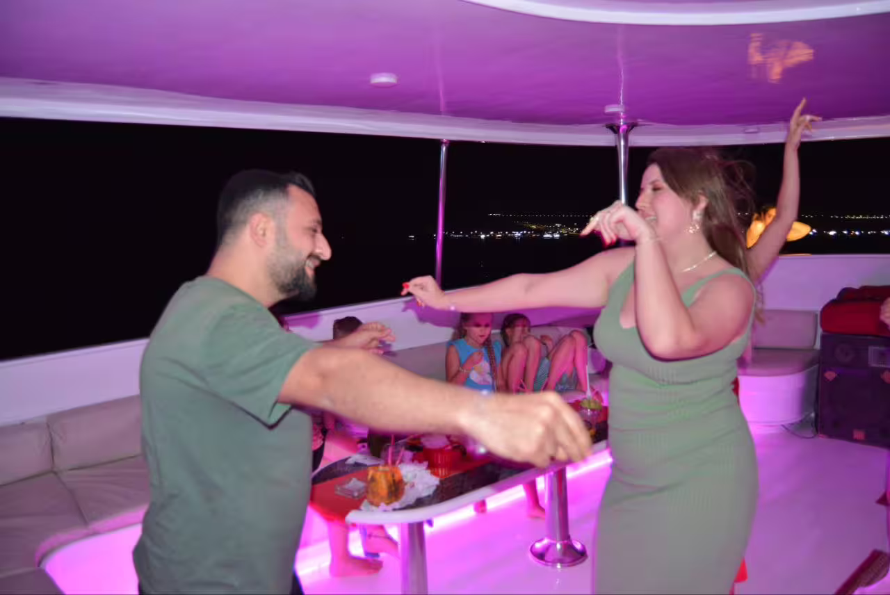 Couple dancing on VIP dinner cruise boat in Sharm El Sheikh with neon lights and Red Sea night views