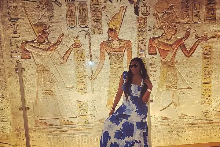 Traveler posing by colorful ancient Egyptian wall carvings in Luxor temple, VIP private day tour from Marsa Alam