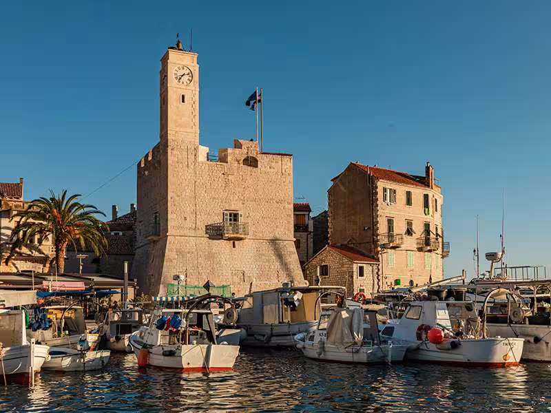 Vis town harbor with historic stone clock tower and boats, scenic stop on Blue Cave tour from Hvar