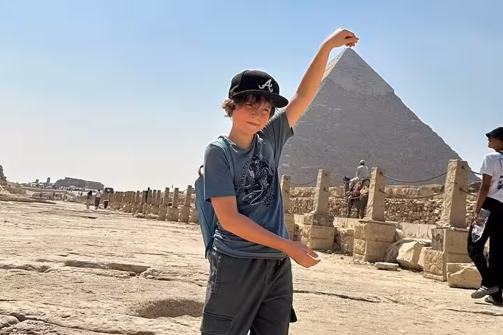 Visitor posing at the Great Pyramid of Giza during a full-day tour with museum and bazaar stops