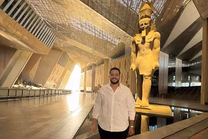 Visitor in Grand Egyptian Museum Cairo beside towering Ramses II statue on Sharm El Sheikh to Cairo tour