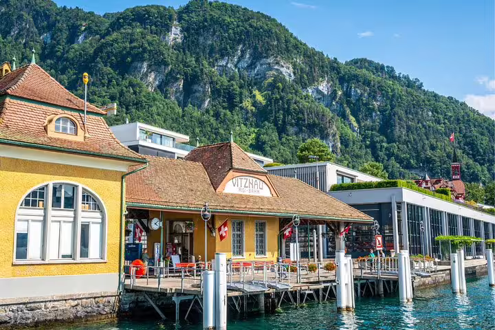 Charming Vitznau station by Lake Lucerne, nestled against lush mountains, ideal for Mount Rigi day trips.