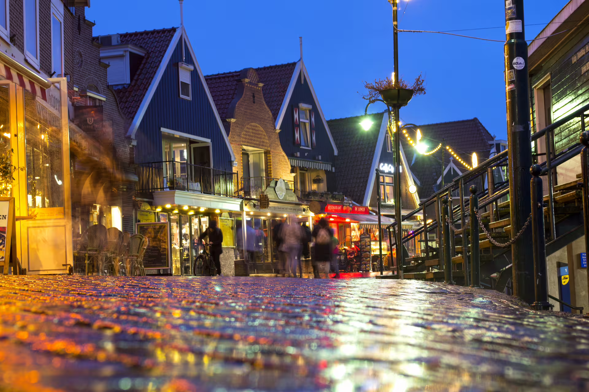 Evening stroll on Volendam dike with lit shops and gabled houses, featured on the 1-day walking tour audioguide