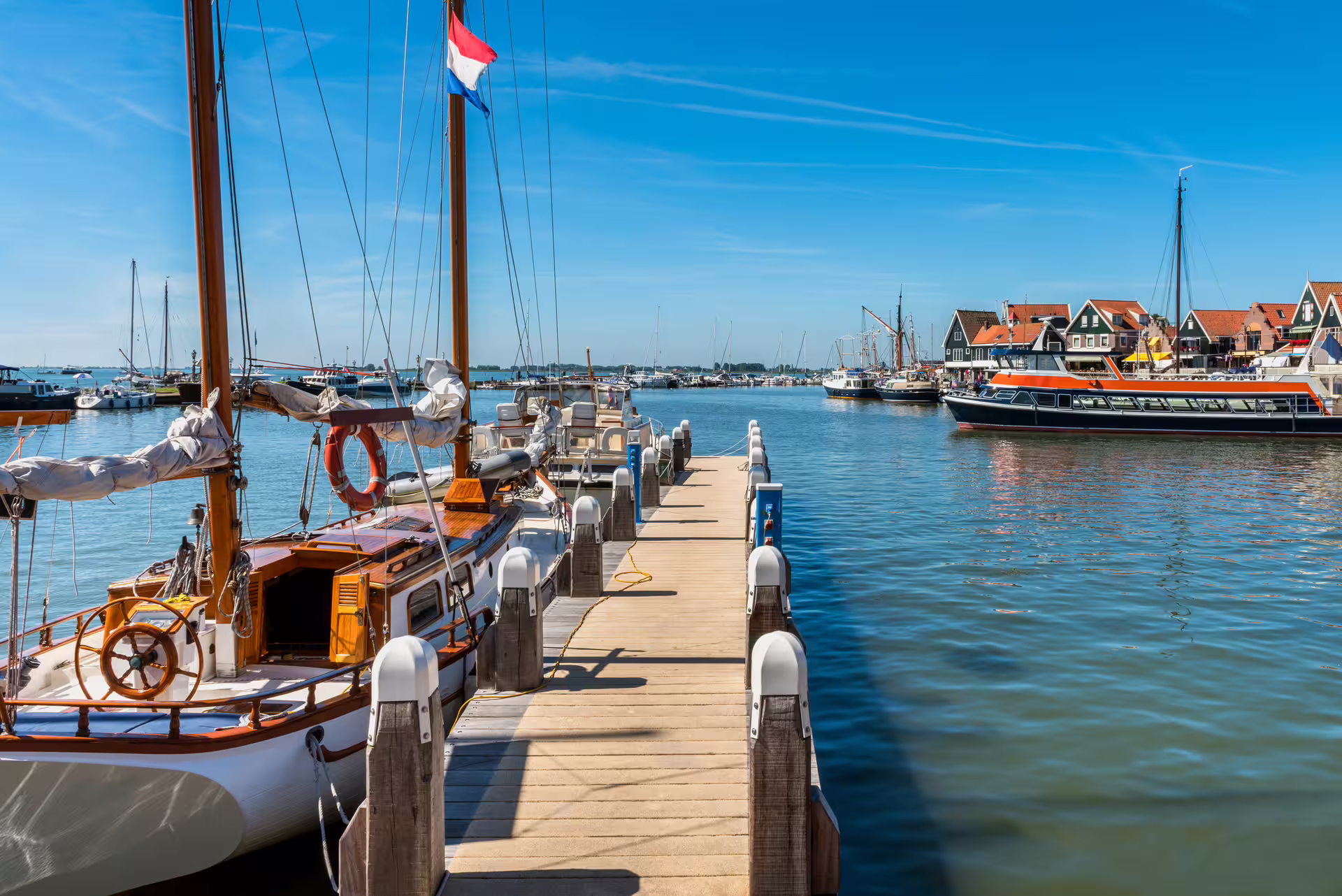 Volendam harbor pier with sailboats and Dutch flag, scenic viewpoint on 1-day walking tour audioguide in 7 languages