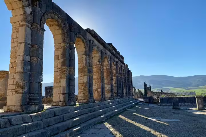 Roman arches at Volubilis ruins near Meknes, scenic stop on a Morocco 12 days tour from Marrakech itinerary