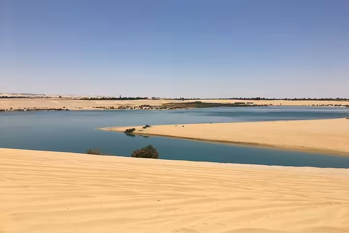 Sand dunes meeting blue water at Wadi El Rayan lakes, a Fayoum oasis landscape on the guided day tour