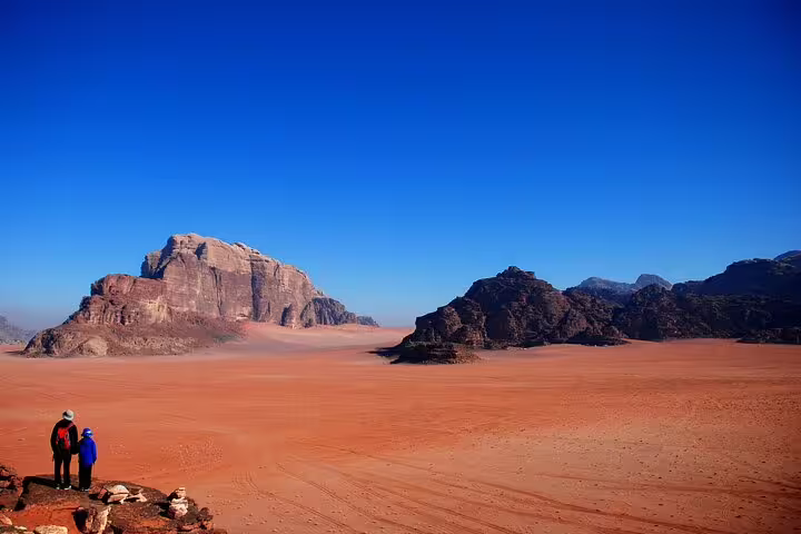 Wide Wadi Rum desert panorama with hikers and sandstone mountains, add-on to Petra tour from Taba by ferry boat