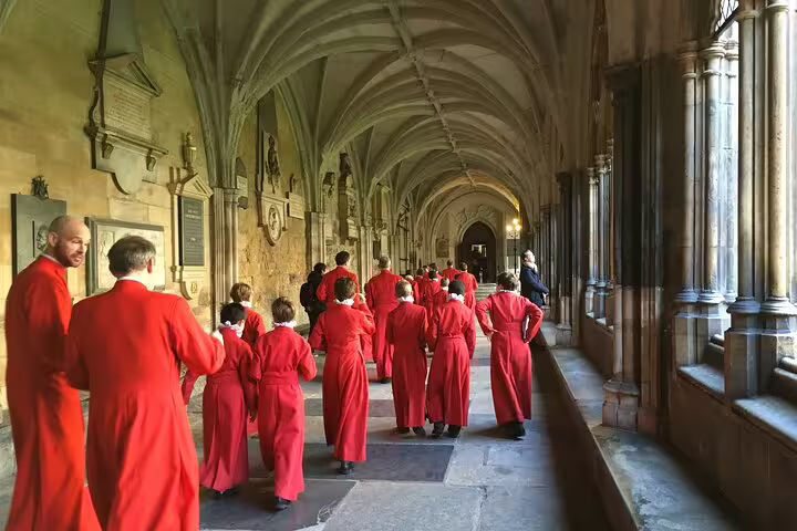 Visitors in red robes walk through the historic cloisters of Westminster Abbey on a private London full-day tour.
