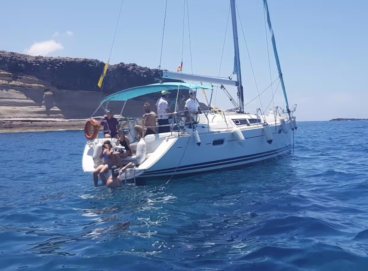 Visitors relax and sunbathe on a yacht during a whale watching tour near Puerto Colón's scenic coastline.