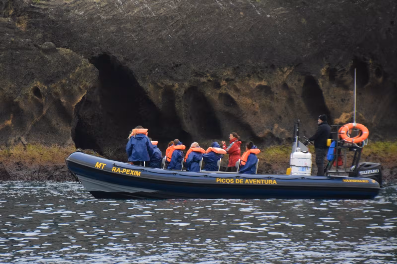 RIB boat with life-jacketed guests cruising rocky north coast on a whale watching expedition, no transport included