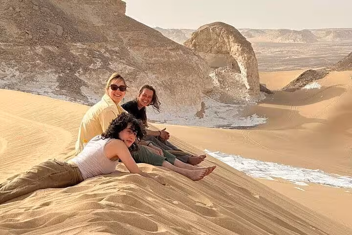 Friends relaxing on sand dune near White Desert formations on a 2-day private White & Black Desert tour, Egypt