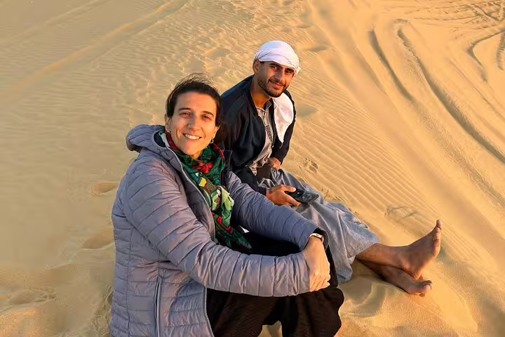 Guests relaxing on golden dunes during White Desert and Bahariya Oasis overnight camping safari in Egypt