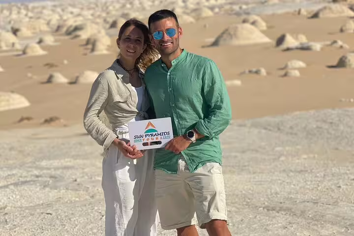 Travelers holding tour sign in White Desert Egypt, exploring Bahariya Oasis on an overnight camping safari