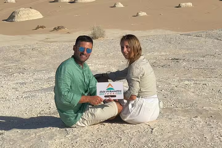 Travelers sitting on White Desert rock plateau with chalk mounds, 3 days 2 nights Bahariya Oasis trip