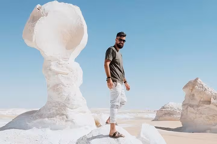 Visitor beside giant chalk mushroom rock in Egypt’s White Desert, part of a White & Black Desert 2-day tour