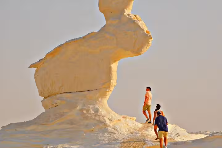 Travelers hiking to White Desert mushroom formation on 3-day Egypt desert camping tour with Black Desert and Djara Cave