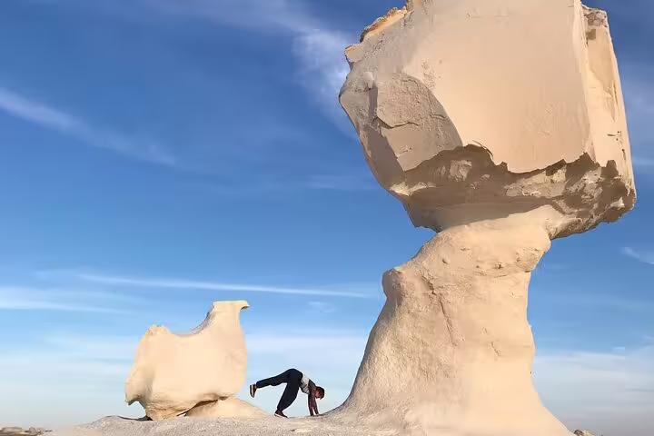 Traveler under giant mushroom rock in Egypt White Desert, iconic stop on 3 days 2 nights Bahariya Oasis tour