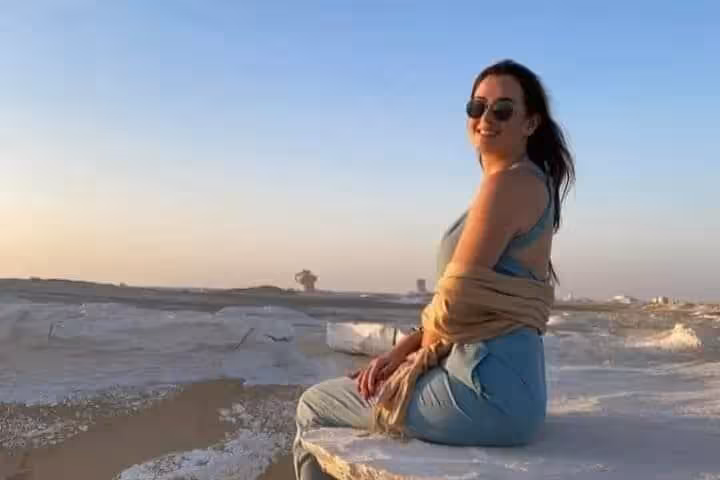 Traveler relaxing on white chalk rock at sunset in Egypt’s White Desert on a 2-day private desert tour