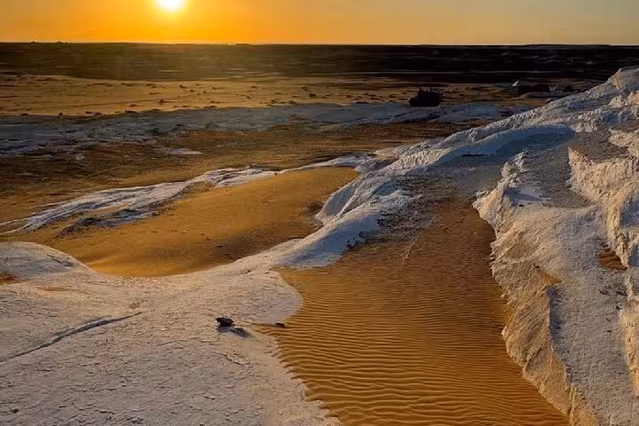 Sunset over White Desert chalk formations and rippled sand dunes on a 2-day private White & Black Desert tour