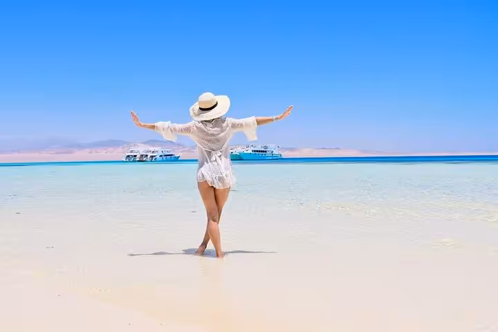 Traveler on White Island sandbar with boats, Red Sea views on Ras Mohammed day trip from Sharm El Sheikh