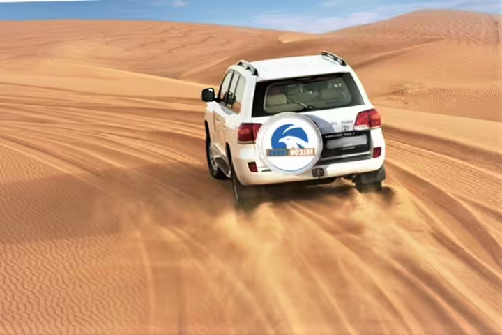 White SUV navigating the golden desert sands of Qatar, showcasing an exhilarating desert safari experience.