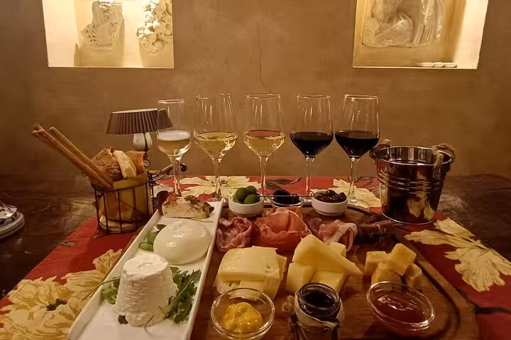 Luxurious wine and food tasting setup featuring assorted cheeses, meats, and six wine glasses for enogastronomy delight.