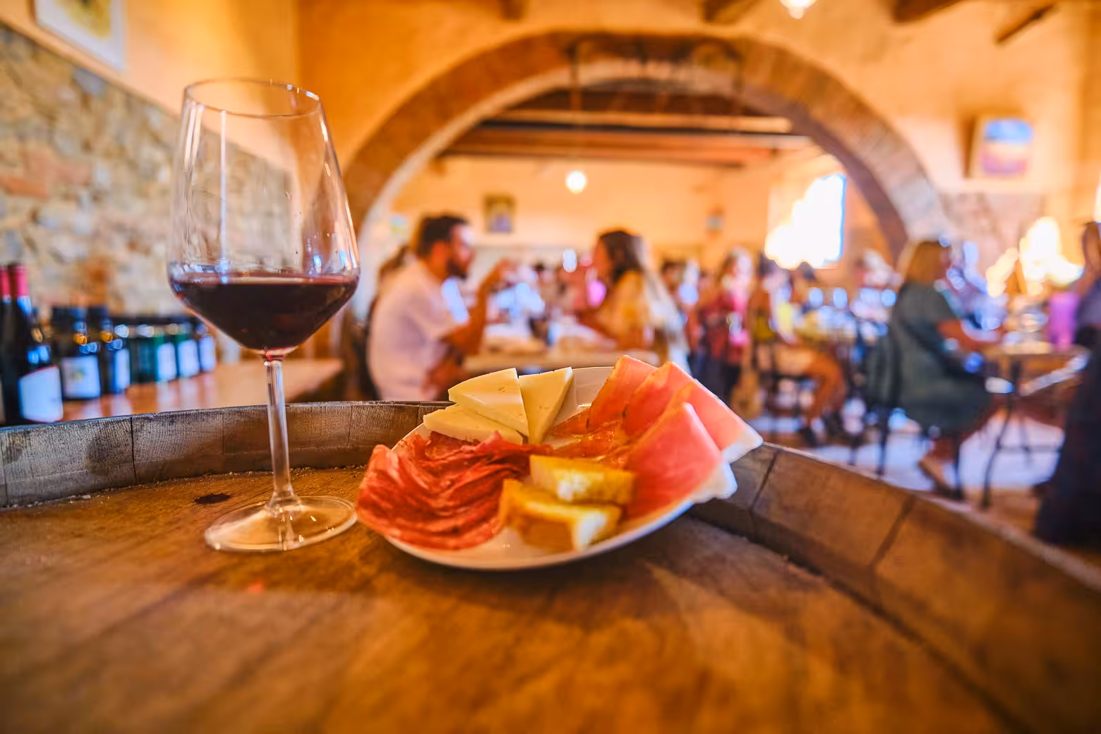 Close-up of wine glass and charcuterie plate in rustic setting, perfect for a wine blending tour.