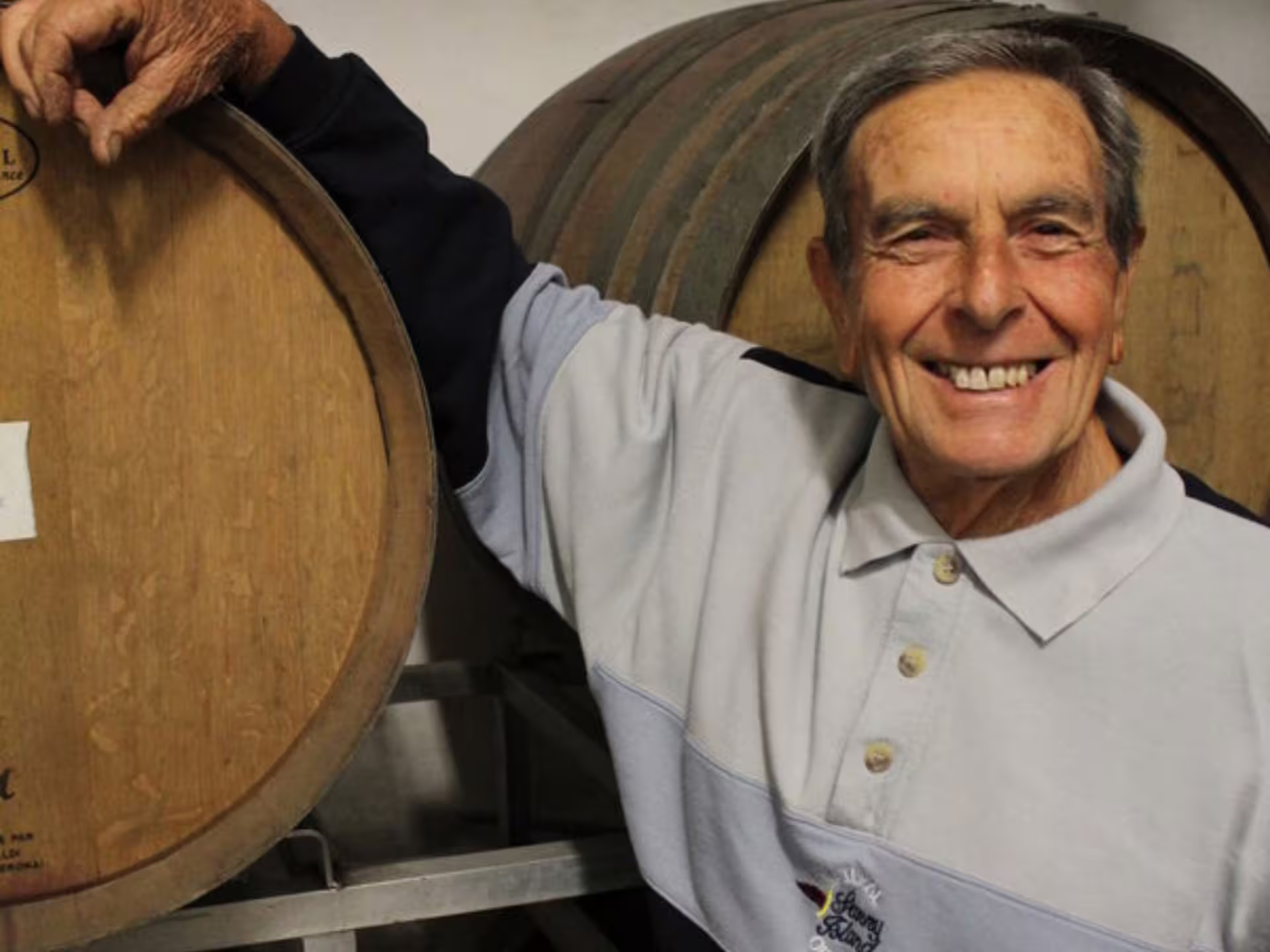 Friendly winemaker smiling beside oak barrels, showcasing artisanal wine production in Castelli Romani.