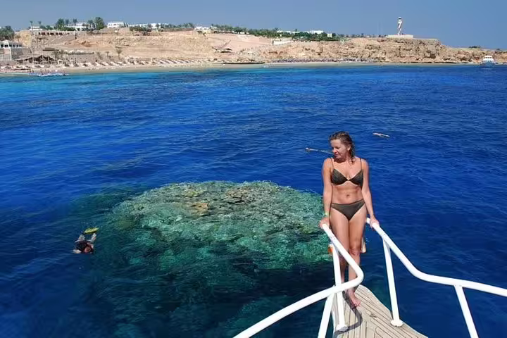 Woman on boat ladder above coral reef at Ras Mohamed Park, Red Sea, on White Island snorkeling tour