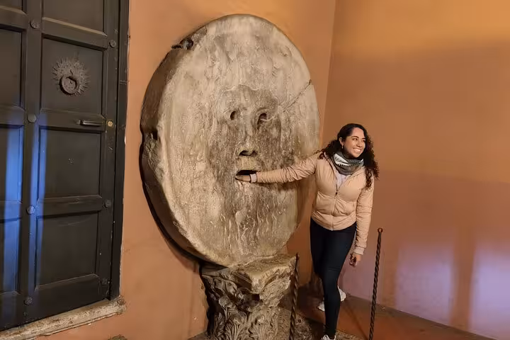 A woman interacts with the legendary Bocca della Verità, enjoying a unique stop on an e-bike tour in Rome.