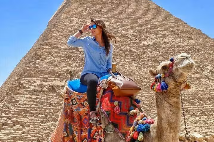 Woman on decorated camel with Great Pyramid of Giza backdrop on Hurghada to Pyramids small group excursion