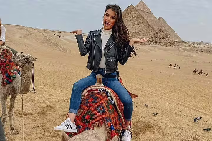 Woman on a camel with the Giza Pyramids behind on a private 3-hour Giza Pyramids and Sphinx camel tour