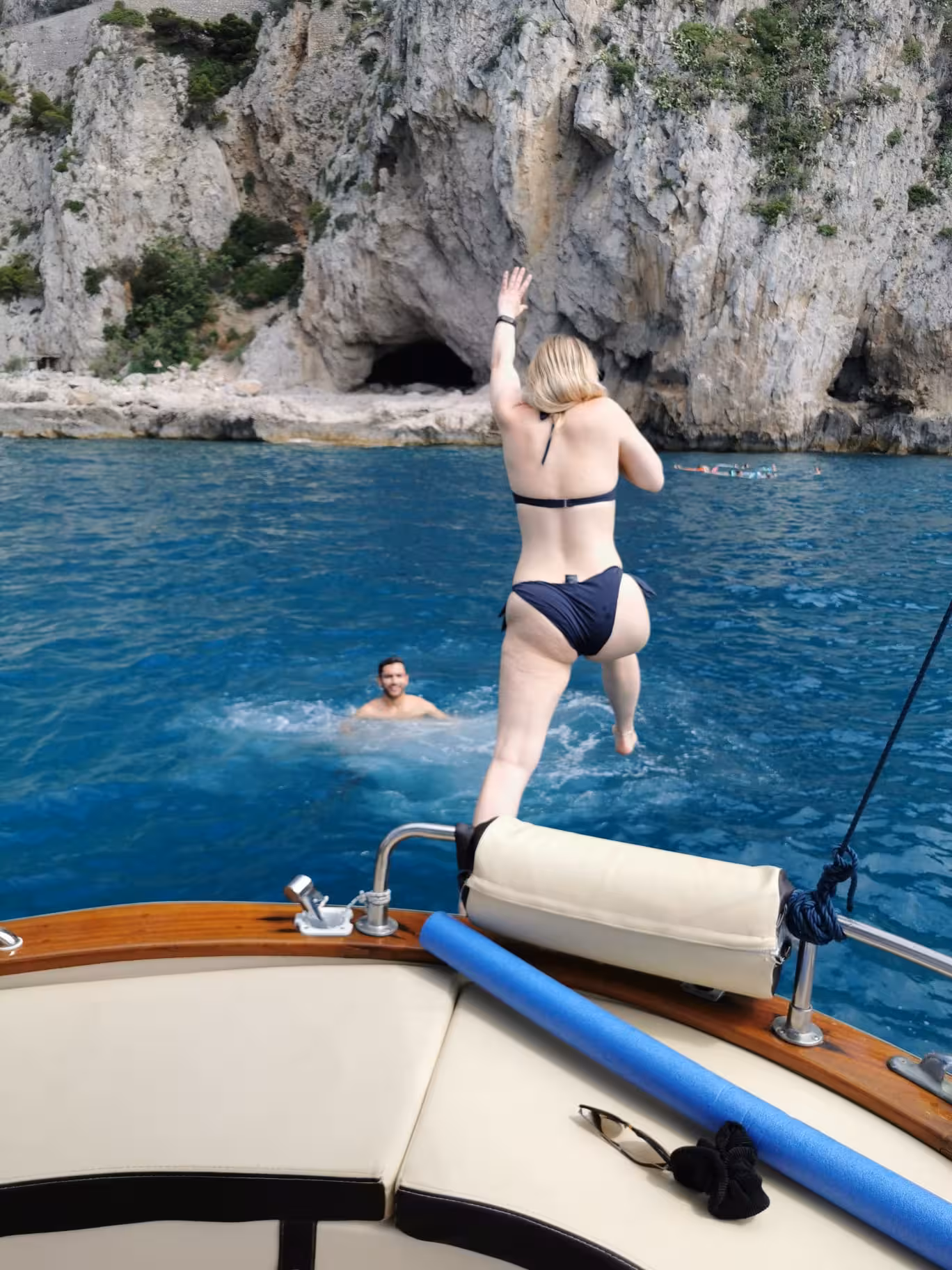 Woman jumping into the crystal-clear waters of Capri during a boat tour from Sorrento.