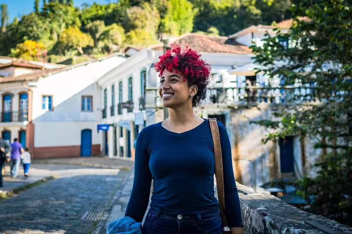 Smiling woman exploring the historic cobblestone streets of Minas Gerais on a sunny day.
