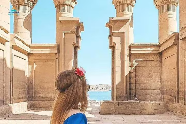 Woman at Philae Temple colonnade overlooking the Nile, private Aswan to Luxor full-day car tour in Egypt