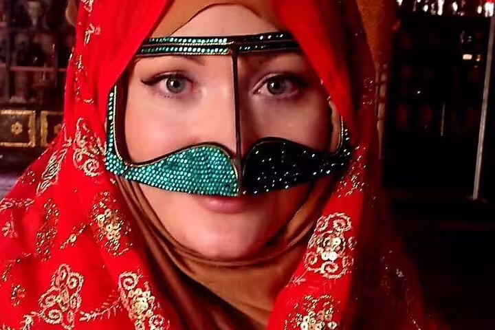 Woman in traditional Omani attire with embellished mask, featured in 5 Days 4 Nights Oman Package Tour Mohammed.