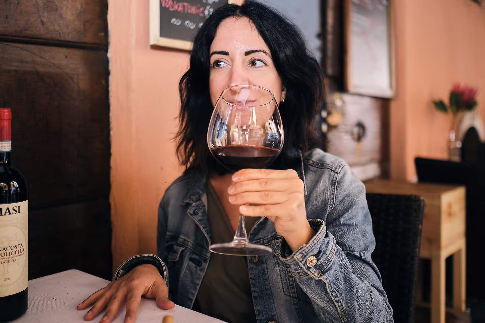 Woman sipping red wine on Verona tasting tour near Juliet’s House, enjoying Valpolicella in a cozy wine bar