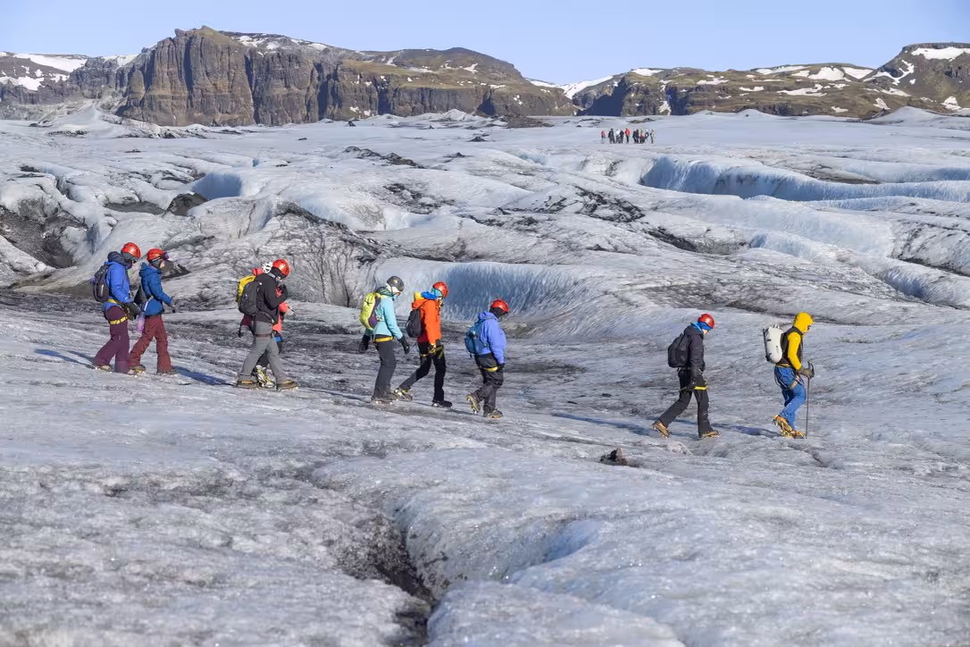 Women equipped for glacier hiking traverse a stunning glacier landscape on the Iceland women's voyage.