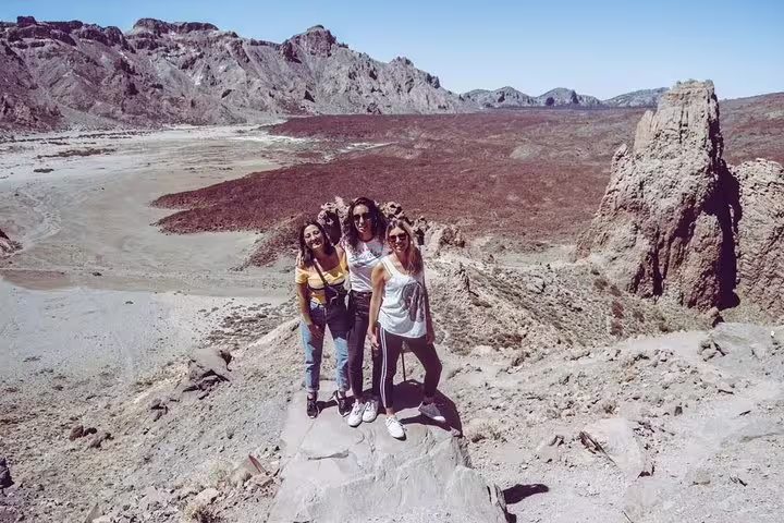 Group of women standing on rocky terrain with expansive volcanic backdrop, great for private cruise tours.