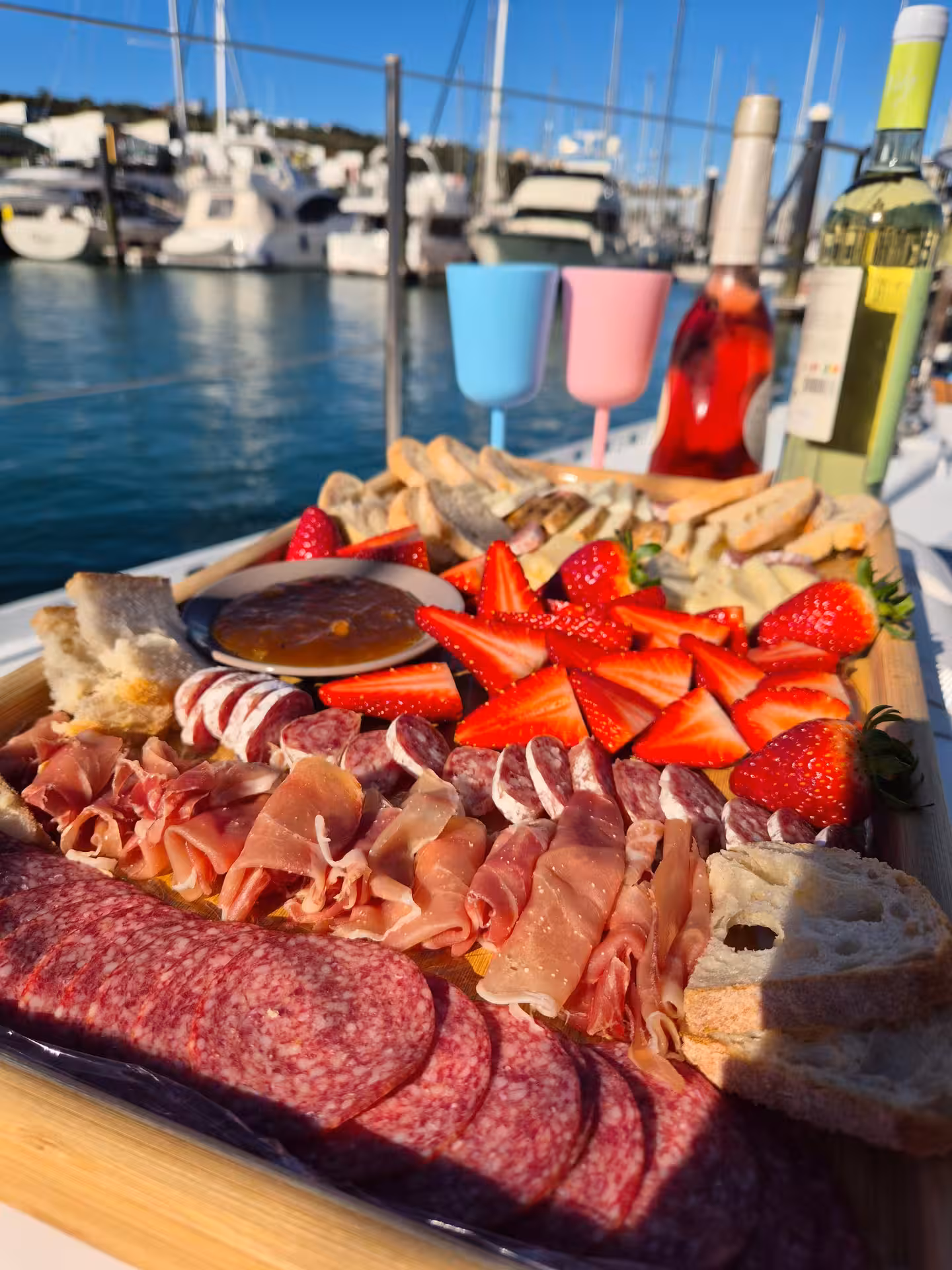Luxurious charcuterie board with meats, cheeses, and strawberries on YACHT FINISMAR under clear blue skies.